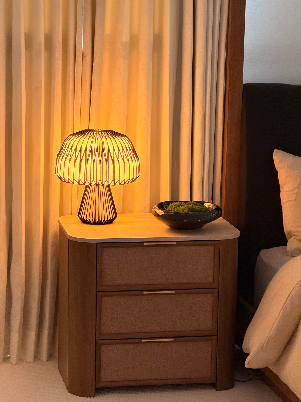 A wire-frame mushroom lamp glowing on a bedside table